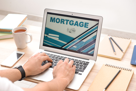 Man using laptop to pay mortgage loan online at homeの写真素材