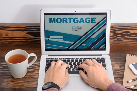 Man using laptop to pay mortgage loan online at table in cafeの写真素材