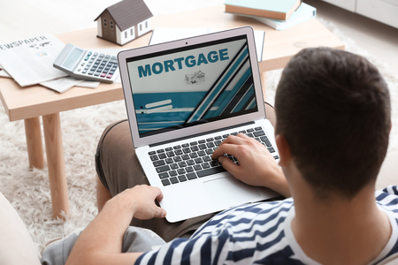 Man using laptop to pay mortgage loan online at homeの写真素材