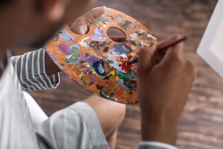 Young African-American artist painting picture in workshop, closeupの写真素材