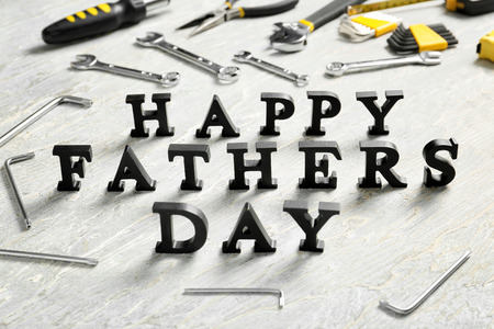 Phrase "Happy Father's Day" composed with letters and different tools on tableの写真素材