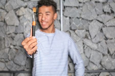 Young African-American artist with brush against stone wallの写真素材