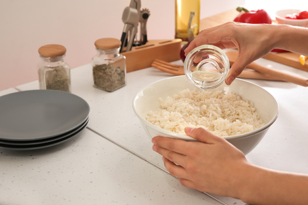 Woman adding oil to boiled rice in bowl, closeupの写真素材