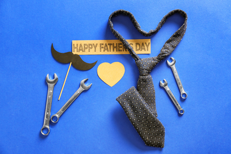 Paper mustache, tools, necktie and tag with text "Happy Father's Day" on color backgroundの写真素材