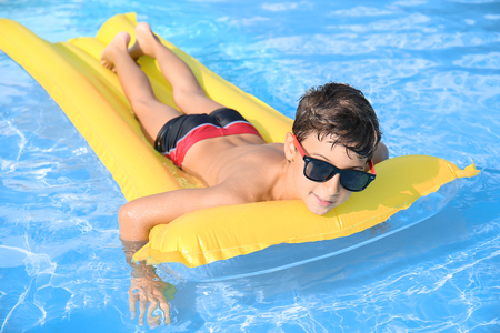 Cute little boy resting on inflatable mattress in swimming poolの写真素材