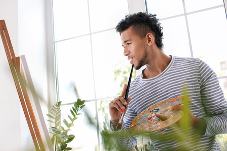 Young African-American artist painting picture at homeの写真素材