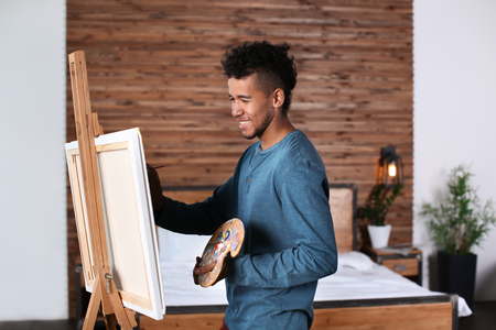 Young African-American artist painting picture at homeの写真素材