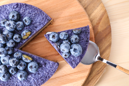 Taking of tasty blueberry cheesecake from board by using shovelの写真素材