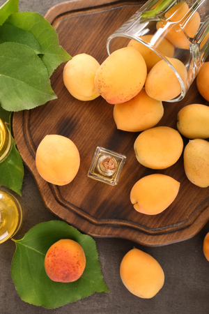 Bottle with essential oil and fresh apricots on boardの写真素材