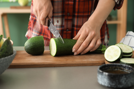 Woman cutting zucchini in kitchenの写真素材