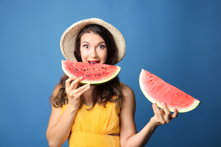 Emotional young woman with slices of tasty watermelon on color backgroundの写真素材