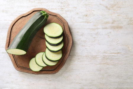Board with ripe cut zucchini on wooden tableの写真素材