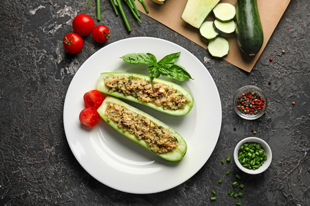 Plate with quinoa stuffed zucchini boats and vegetables on grunge tableの写真素材