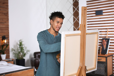 Young African-American artist painting picture at homeの写真素材