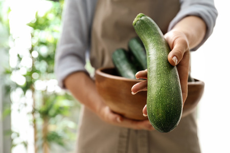 Woman holding fresh zucchini, closeupの写真素材