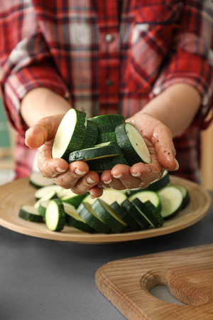 Woman holding sliced zucchini over plate, closeupの写真素材