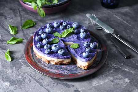 Plate with tasty blueberry cheesecake on dark tableの写真素材