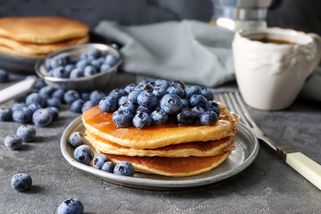 Plate with tasty pancakes and blueberries on dark tableの写真素材