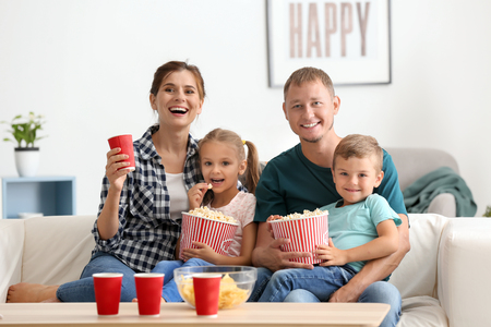 Family eating popcorn while watching TV at homeの写真素材