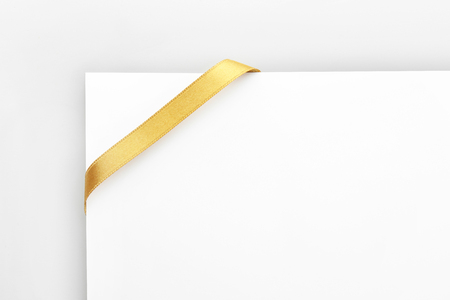 Beautiful golden ribbon with blank card on white backgroundの写真素材