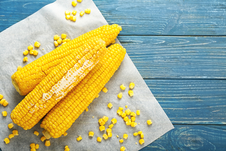 Tasty corn cobs with butter on wooden tableの写真素材