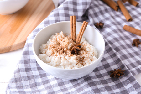 Bowl with delicious rice pudding and cinnamon powder on tableの写真素材