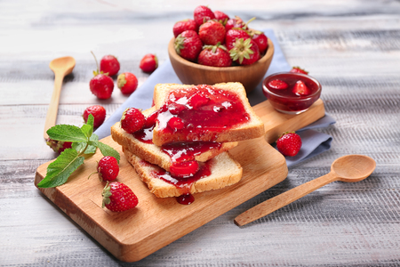Composition with slices of bread and delicious strawberry jam on wooden tableの写真素材