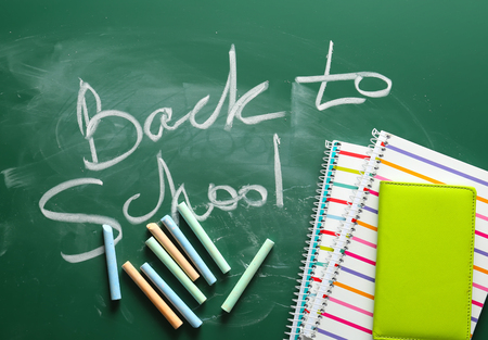 Notebooks, crayons and words BACK TO SCHOOL written on chalkboardの写真素材