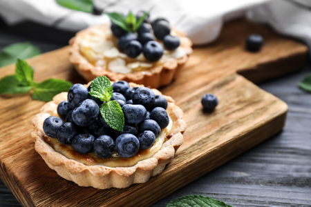 Wooden board with delicious blueberry tart on grey tableの写真素材
