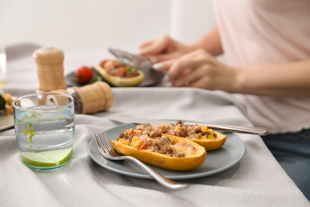Plate with meat stuffed zucchini boats and glass of water on tableの写真素材