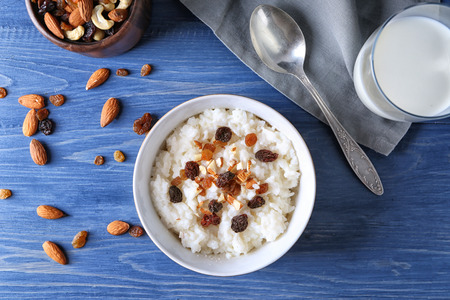 Bowl with delicious rice pudding, nuts and raisins on wooden tableの写真素材