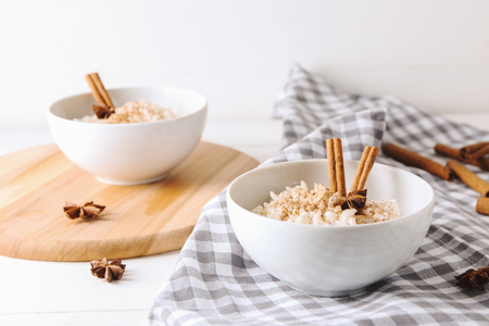 Bowls with delicious rice pudding and cinnamon powder on tableの写真素材