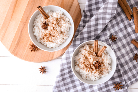 Bowls with delicious rice pudding and cinnamon powder on tableの写真素材