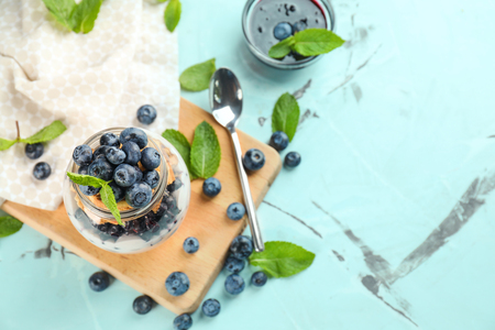 Glass jar with delicious blueberry dessert on light tableの写真素材