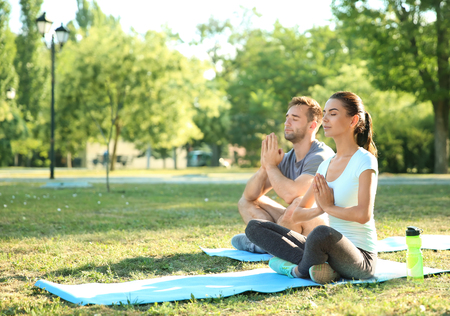Group of sporty people practicing yoga in parkの写真素材