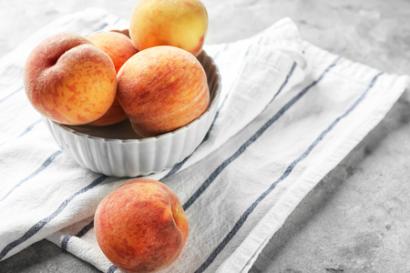 Bowl with fresh peaches on light tableの写真素材