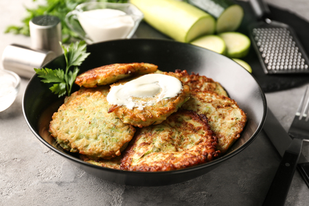 Plate with zucchini pancakes and sauce on tableの写真素材