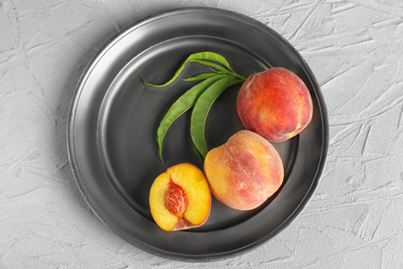 Plate with fresh peaches on light tableの写真素材