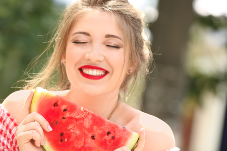 Beautiful young woman with slice of tasty watermelon outdoorsの写真素材