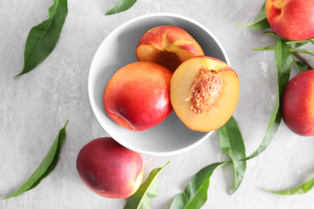 Bowl with fresh sweet peaches on light tableの写真素材