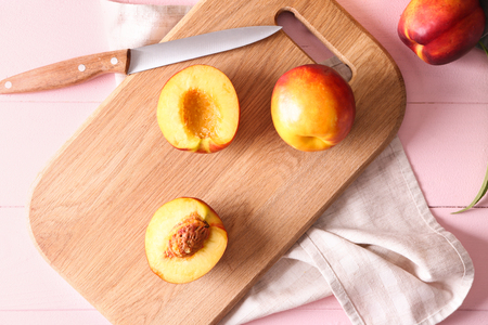 Fresh sweet peaches with knife on wooden boardの写真素材