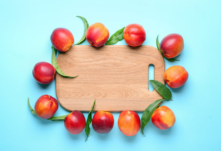 Composition with ripe peaches and wooden board on color background, top viewの写真素材