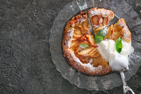 Plate with delicious peach galette and ice-cream on grunge tableの写真素材