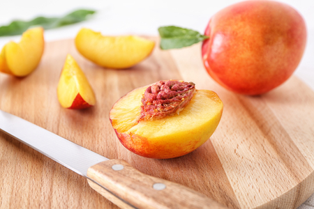Fresh cut peach with knife on wooden board, closeupの写真素材