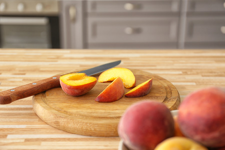 Board with sliced peaches on wooden tableの写真素材
