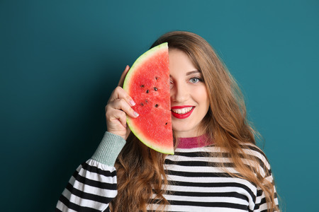 Beautiful young woman with slice of tasty watermelon on color backgroundの写真素材