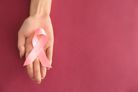Woman holding pink ribbon on color background. Breast cancer awareness conceptの写真素材