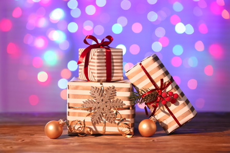 Beautiful Christmas gift boxes with decorations on table against blurred lightsの写真素材