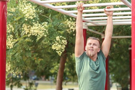 Sporty young man training on athletic field outdoors