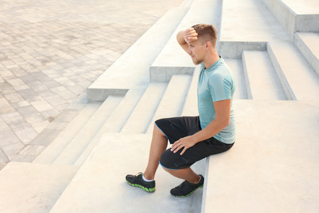 Sporty young man resting after training outdoorsの写真素材